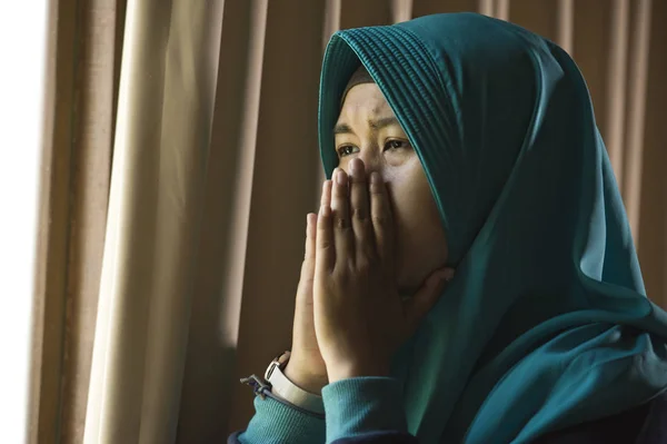 年轻悲伤和沮丧的穆斯林妇女的生活方式肖像在伊斯兰教传统的 Hijab 头围巾在家里的窗口感到不适忍受抑郁症危机和焦虑问题哭泣无助 — 图库照片