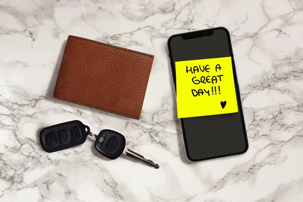 have a great day romantic and sweet handwritten note on yellow posit stick to mobile phone next to car key and leather wallet in woman leaving love message in husband belongings on table