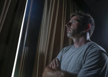 dramatik ışık kapalı portre çekici genç üzgün ve depresyonda adam ev oda pencere düşünceli ve dalgın depresyon sorunu ve anksiyete krizi acı acı içinde aramak