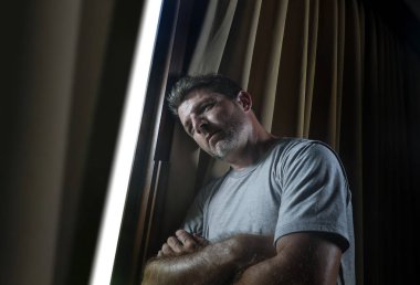 dramatik ışık kapalı portre çekici genç üzgün ve depresyonda adam ev oda pencere düşünceli ve dalgın depresyon sorunu ve anksiyete krizi acı acı içinde aramak