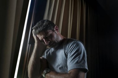 dramatik ışık kapalı portre çekici genç üzgün ve depresyonda adam ev oda pencere düşünceli ve dalgın depresyon sorunu ve anksiyete krizi acı acı içinde aramak
