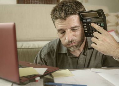 Genç vurguladı ve oturma odası hesap makinesi ve iç muhasebe evrakları duygu yapıyor dizüstü kullanarak para vergi giderleri ve mali durum bunalmış adam evde endişeli