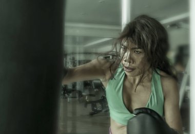 Dövüş, boks eldivenli ağır çanta delme genç atletik ve fit çekici Asya savaşçı kadın zor egzersiz terli ve öfkeli öğrenme saldırı yapmak spor kulübü ve teknik savunma