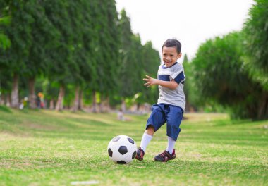 çimen Şehir Parkı 5 yıllık yaşam tarzı resme eski Asya Endonezya çocuk mutlu ve heyecanlı çocuk spor pratik eğitim ve genç futbol fan içinde neşeli gülümseyen topu tekmeleme futbol oynarken 