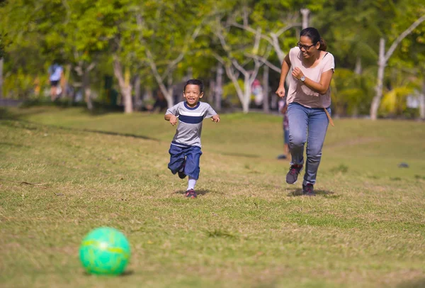 少しアジア インドネシア母再生サッカーの都市公園における肖像画笑って一緒に実行している息子が興奮して 年間楽しんでサッカーのファンの子と健康教育 — ストック写真