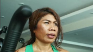 belirlenen genç yüz atış kapatın ve atletik Asya Endonezya spor kadın eğitim fitness salonunda sağlıklı yaşam konsepti eliptik makinesi egzersiz yaparken çalışkan