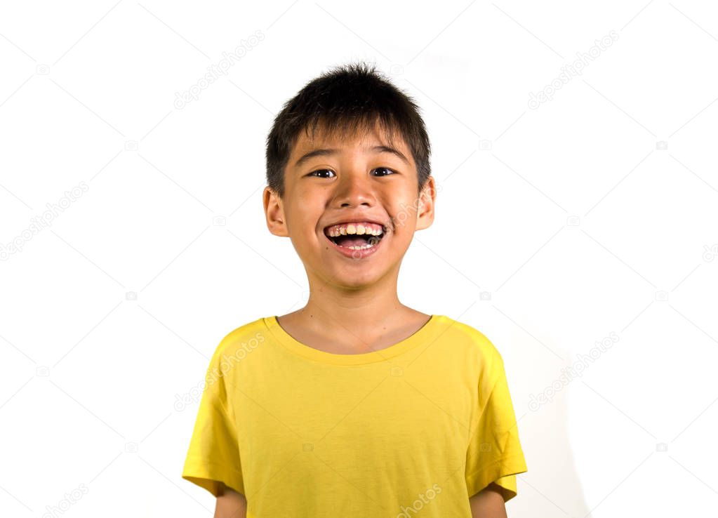 portrait of young happy and excited child smiling and laughing cheerful wearing yellow t-shirt isolated on white background in kid happiness and joyful face expression concept