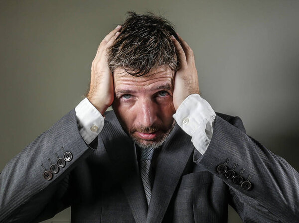 desperate and stressed businessman holding his head frustrated and worried crying suffering depression problem and anxiety crisis isolated on grey background in corporate company failure job