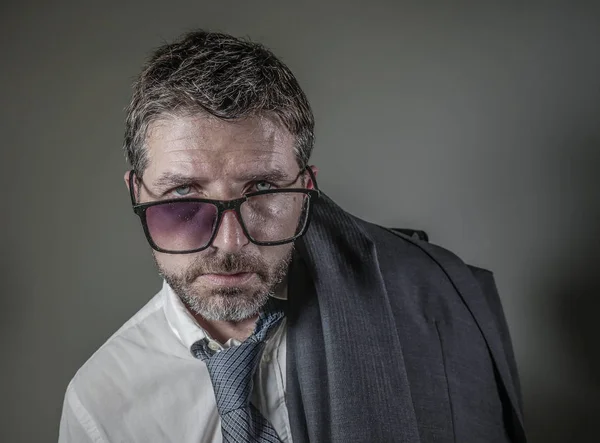 hilarious portrait of 40s weird and wasted businessman in suit and tie wearing ridiculous big broken nerdy glasses posing exhausted feeling a loser isolated on grey background as unsuccessful man