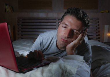 yalan ve yatağa evde yatak uyku veya iş projesi son tarih stres içinde uykuya gece geç dizüstü bilgisayar ile çalışma uykulu ağ genç yorgun ve çok çalışan adam 