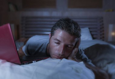 yalan ve yatağa evde yatak uyku veya iş projesi son tarih stres içinde uykuya gece geç dizüstü bilgisayar ile çalışma uykulu ağ genç yorgun ve çok çalışan adam 