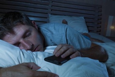 Genç yaşam tarzı portresi yorgun ve bitkin uyku veya süre yatakta ağ Internet gece geç saatlerde uykuya adam ve sosyal medya akıllı telefon bağımlılığı ve kavram çok