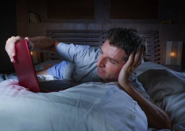 evde ağ genç çekici ve rahat adam yatağa geç gece mutlu film seyrederken dizüstü bilgisayar veya Internet sosyal medya neşeli ve memnun seyir zevk rahat yalan