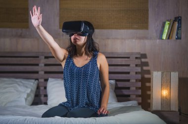 genç çekici heyecanlı ve mutlu kız giyiyor Vr sanal gerçeklik gaming mezartaşı zevk oynarken dijital 3d deneyimi izlerken ve yatakta yanılsama dokunmadan hayrete düşürdü.