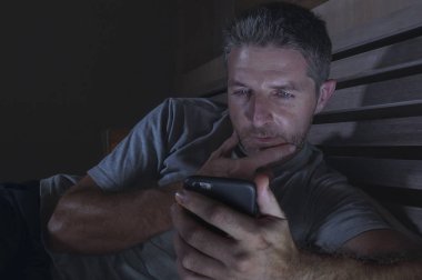 genç yakışıklı ve çekici mutlu adam cep telefonu sosyal medya zevk veya internet bağımlılığı app dating online rahat yatak gülümseyen içinde gece geç ile ağ 
