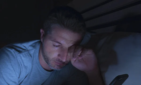 在互联网和社交媒体在线应用成瘾的概念中 深夜躺在家里卧室的床上 生活方式描绘了年轻疲惫和困倦的男人网络 — 图库照片