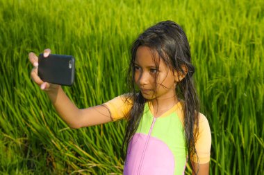 7 veya 8 yaşında tatlı ve güzel kadın çocuğa açık havada pirinç alan çocuk ve internet tatil zevk cep telefonu kamera ile selfie portre fotoğraf çekme manzara teknoloji kavramı