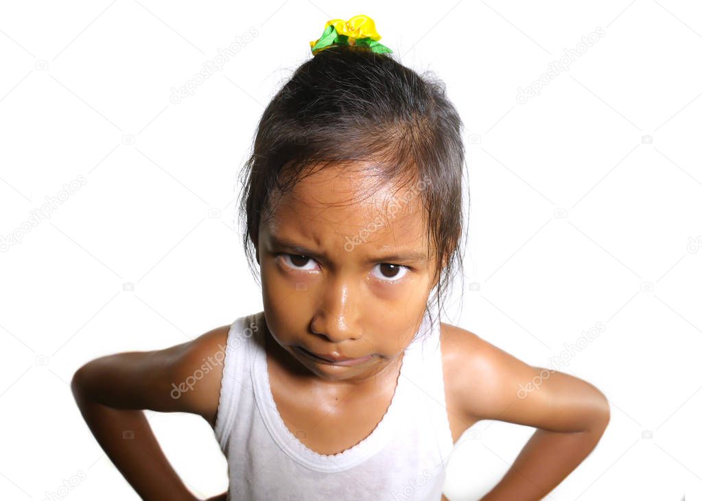 head and shoulders portrait of sweet upset and disappointed 7 years old Asian girl looking intense to the camera feeling angry and unhappy in moody pose 