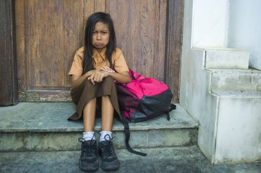 7 veya 8 yıl çocuk açık havada üzgün ve depresyonda ona zorbalık acı sırt çantası ve çaresiz hissediyor bağımlılığı sorunu tutarak ağlamaya katta oturan okul üniformalı