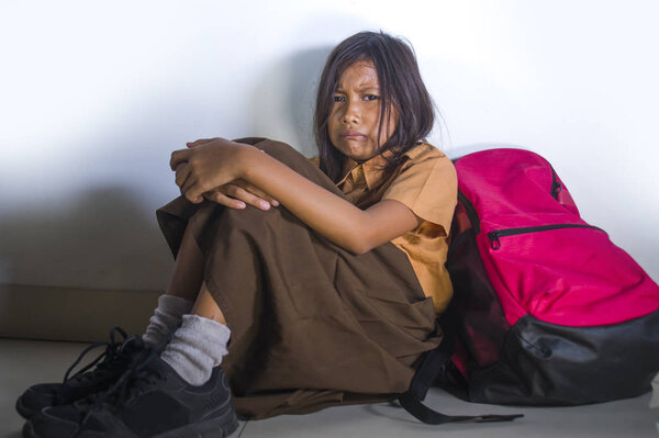 грустный и депрессивный 8 или 9 лет ребенок в школьной форме сидит на полу с ее плохо плачет беспомощное чувство страха и отчаянные страдания запугивания
