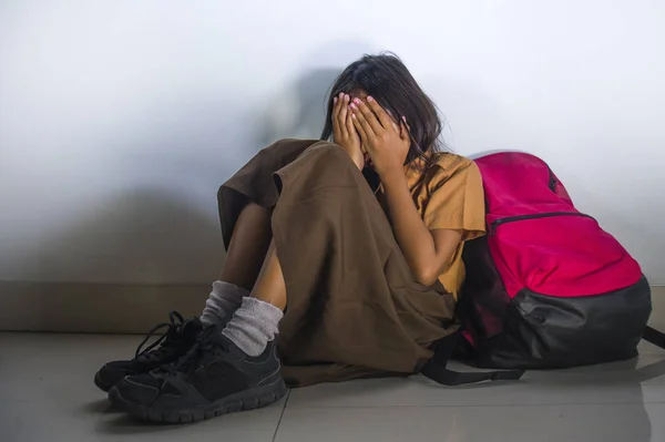 Depressed 8 or 9 years old child in school uniform sitting on the floor with her bad crying helpless feeling scared and desperate suffering bullying and abuse — Stock Photo, Image