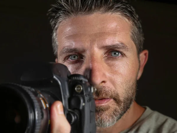 Attrayant et bel homme sur son 30d tenant appareil photo reflex professionnel à côté de son visage isolé sur fond noir dans le passe-temps de la photographie — Photo