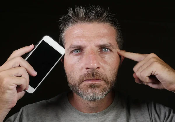 Jovem atraente e bonito viciado em internet homem segurando telefone celular contra seu rosto no aplicativo de mídia social e on-line namoro vício isolado no fundo preto — Fotografia de Stock