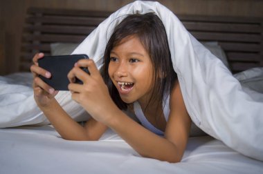mutlu ve güzel 7 yaşında çocuk eğlence oyun internet oyun cep telefonu yatak neşeli ve heyecanlı genç kız ve teknoloji kavramı içinde yatan ile