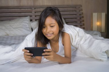 mutlu ve güzel 7 yaşında çocuk eğlence oyun internet oyun cep telefonu yatak neşeli ve heyecanlı genç kız ve teknoloji kavramı içinde yatan ile