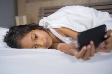 mutlu ve güzel 7 yaşında çocuk eğlence oyun internet oyun cep telefonu yatak neşeli ve heyecanlı genç kız ve teknoloji kavramı içinde yatan ile