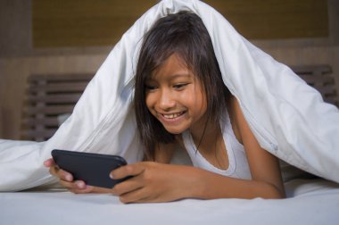 eğlenceli olan mutlu ve güzel yedi yaşındaki çocuğun yatakta neşeli ve heyecanlı çocuk ve aile içi teknoloji kavramı yalan cep telefonunuzla internet oyun oynarken
