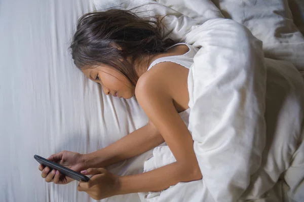 Fericit și frumos copil de 7 ani care se distrează jucând joc pe internet cu telefonul mobil culcat pe pat vesel și entuziasmat în conceptul de tehnologie pentru copii și domestici — Fotografie, imagine de stoc