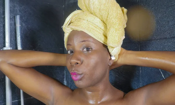 Lifestyle πορτρέτο του νεαρή όμορφη μαύρη γυναίκα αφρικανική αμερικανική κατοχή ενός ντους με το κεφάλι τυλιγμένο σε μια πετσέτα χαμογελώντας χαρούμενα στην υγιεινή και ομορφιά — Φωτογραφία Αρχείου