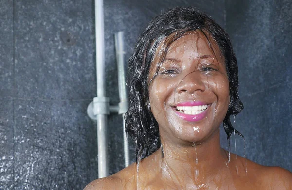 Εγχώρια lifestyle πορτρέτο των νέων ευτυχισμένη και όμορφη μαύρη αφρικανική αμερικανική γυναίκα που χαμογελά ευτυχισμένη λαμβάνοντας ένα ντους στο μπάνιο στο σπίτι το λούσιμο με σαμπουάν — Φωτογραφία Αρχείου