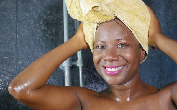Lifestyle πορτρέτο του νεαρή όμορφη μαύρη γυναίκα αφρικανική αμερικανική κατοχή ενός ντους με το κεφάλι τυλιγμένο σε μια πετσέτα χαμογελώντας χαρούμενα στην υγιεινή και ομορφιά — Φωτογραφία Αρχείου