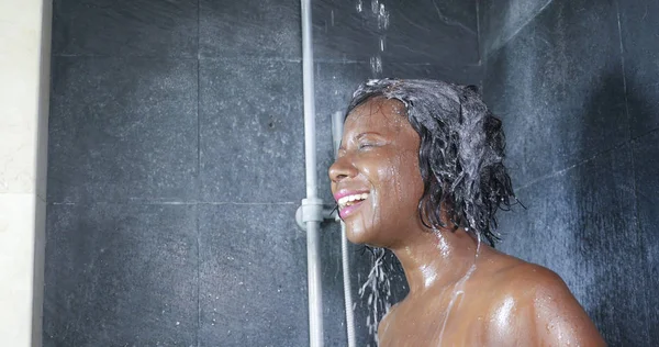 Binnenlandse levensstijl portret van jonge gelukkig en mooie zwarte Afro-Amerikaanse vrouw die lacht gelukkig nemen van een douche in huis badkamer haar met shampoo wassen — Stockfoto