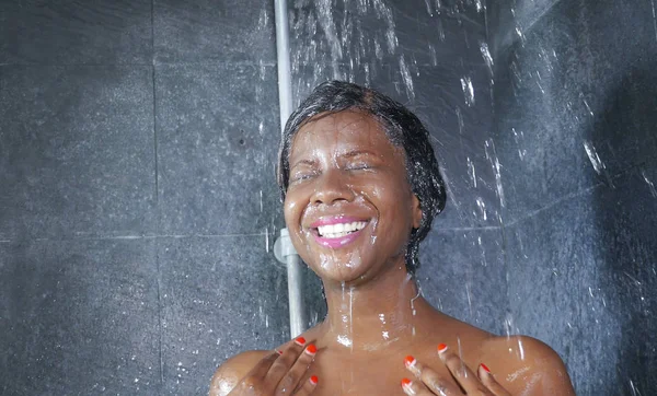 Binnenlandse levensstijl portret van jonge gelukkig en mooie zwarte Afro-Amerikaanse vrouw die lacht gelukkig nemen van een douche in huis badkamer haar met shampoo wassen — Stockfoto