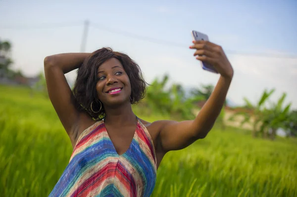Mutlu ve çekici siyah afro Amerikalı kadın zevk internet cep telefonu ile selfie portre çekici güzel elbiseli Asya pirinç alan neşeli gülümseyen içinde seyahat tatil — Stok fotoğraf