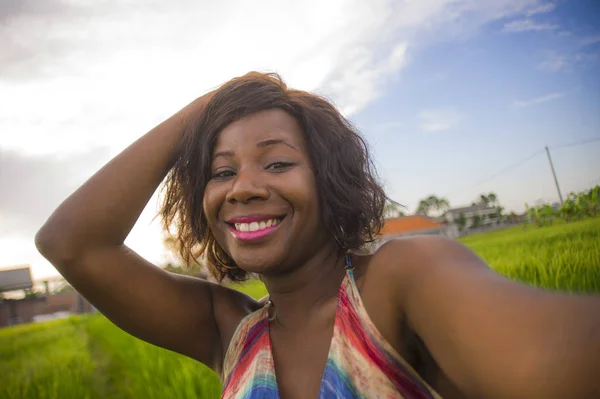Feliz e atraente mulher negra afro-americana em belo vestido tomando selfie retrato com internet telefone celular desfrutando de férias viajar na Ásia sorrindo alegre no campo de arroz — Fotografia de Stock