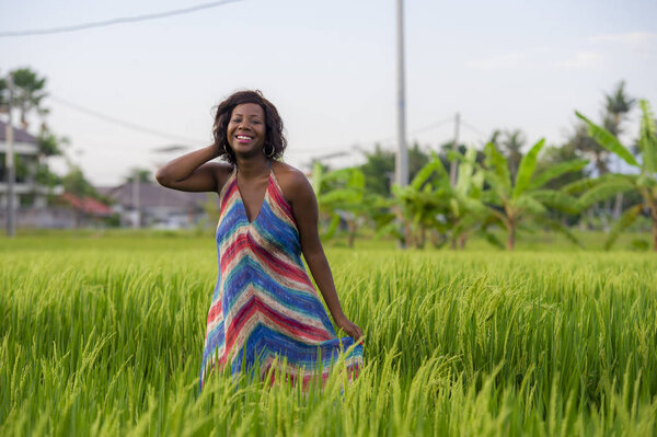 lifestyle portrait of young attractive and happy black African American woman posing cheerful having fun outdoors at beautiful rice field background enjoying holidays trip 