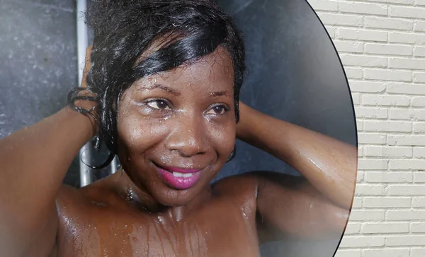 Style de vie domestique miroir reflet portrait de jeune heureuse et belle femme noire afro-américaine souriant gai prendre une douche à la maison salle de bain laver ses cheveux — Photo