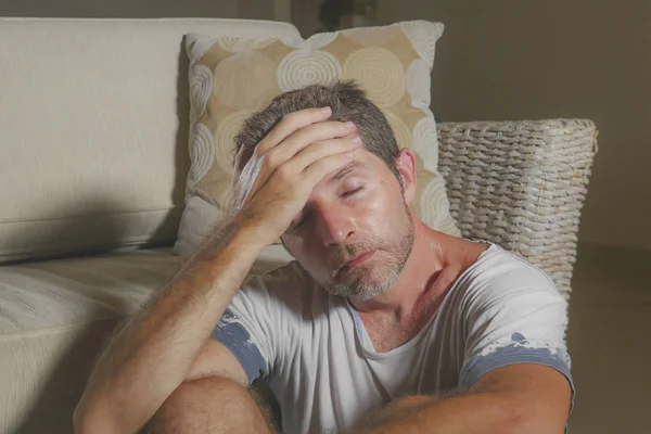 Lifestyle portrait young attractive sad and depressed man sitting on living room floor feeling desperate and stressed suffering depression and anxiety problem looking frustrated — Stock Photo, Image