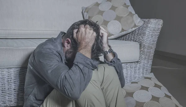 Lifestyle portrait young attractive sad and depressed man sitting on living room floor feeling desperate and stressed suffering depression and anxiety problem looking frustrated — Stock Photo, Image