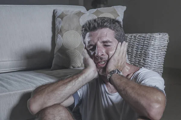 Lifestyle portrait young attractive sad and depressed man sitting on living room floor feeling desperate and stressed suffering depression and anxiety problem looking frustrated — Stock Photo, Image