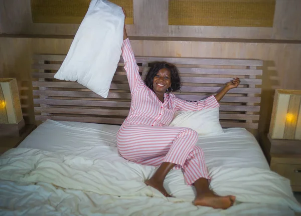 Молодая счастливая и красивая черная афро американка в пижаме лежала расслабленной и игривой на кровати улыбаясь веселый и позитивный просыпаясь утром оптимистичный и свежий — стоковое фото