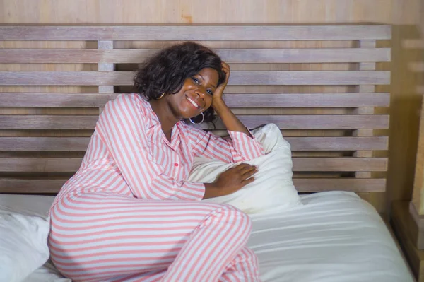 Giovane donna afro americana felice e bella in pigiama sdraiato rilassato e giocoso sul letto sorridente allegro e positivo svegliarsi al mattino ottimista e fresco — Foto Stock