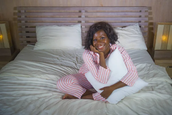 Jovem feliz e bonita negra afro americano mulher de pijama deitado relaxado e brincalhão na cama sorrindo alegre e positivo acordar de manhã otimista e fresco — Fotografia de Stock