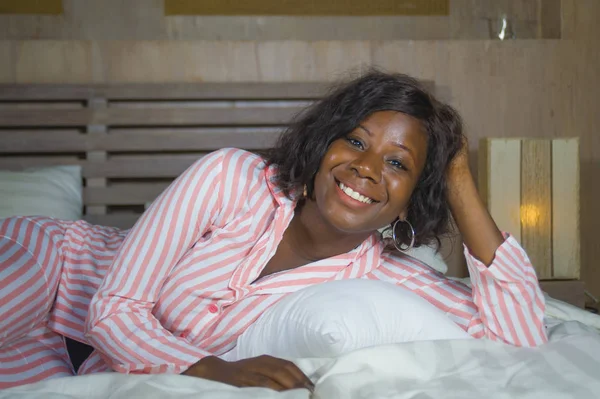 Young happy and beautiful black afro American woman in pajamas lying relaxed and playful on bed smiling cheerful and positive waking up in the morning optimistic and fresh — Stock Photo, Image