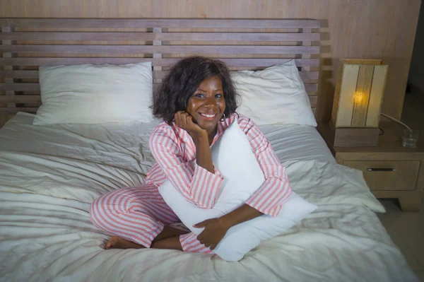 Joven feliz y hermoso negro afroamericano mujer en pijama acostado relajado y juguetón en la cama sonriente alegre y positivo despertar por la mañana optimista y fresco — Foto de Stock