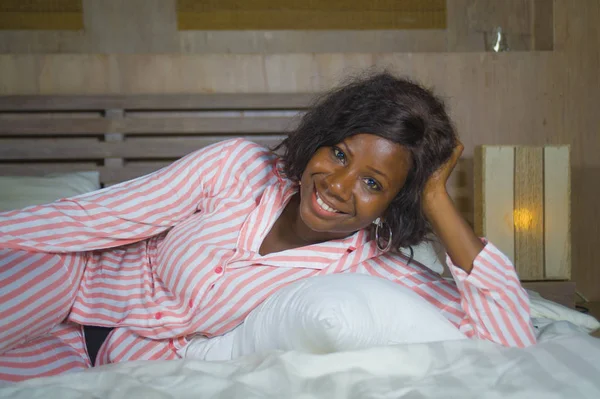 Young happy and beautiful black African American woman in pajamas lying relaxed and playful on bed smiling cheerful and positive waking up in the morning optimistic and fresh — Stock Photo, Image
